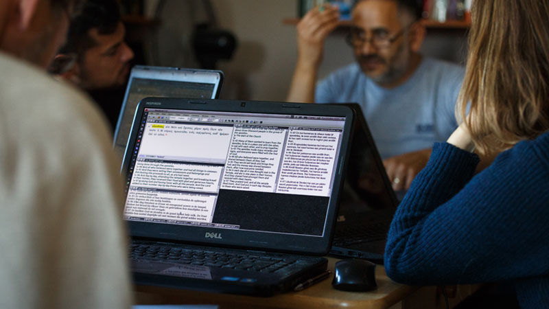 Group of translators working together around a table with laptop